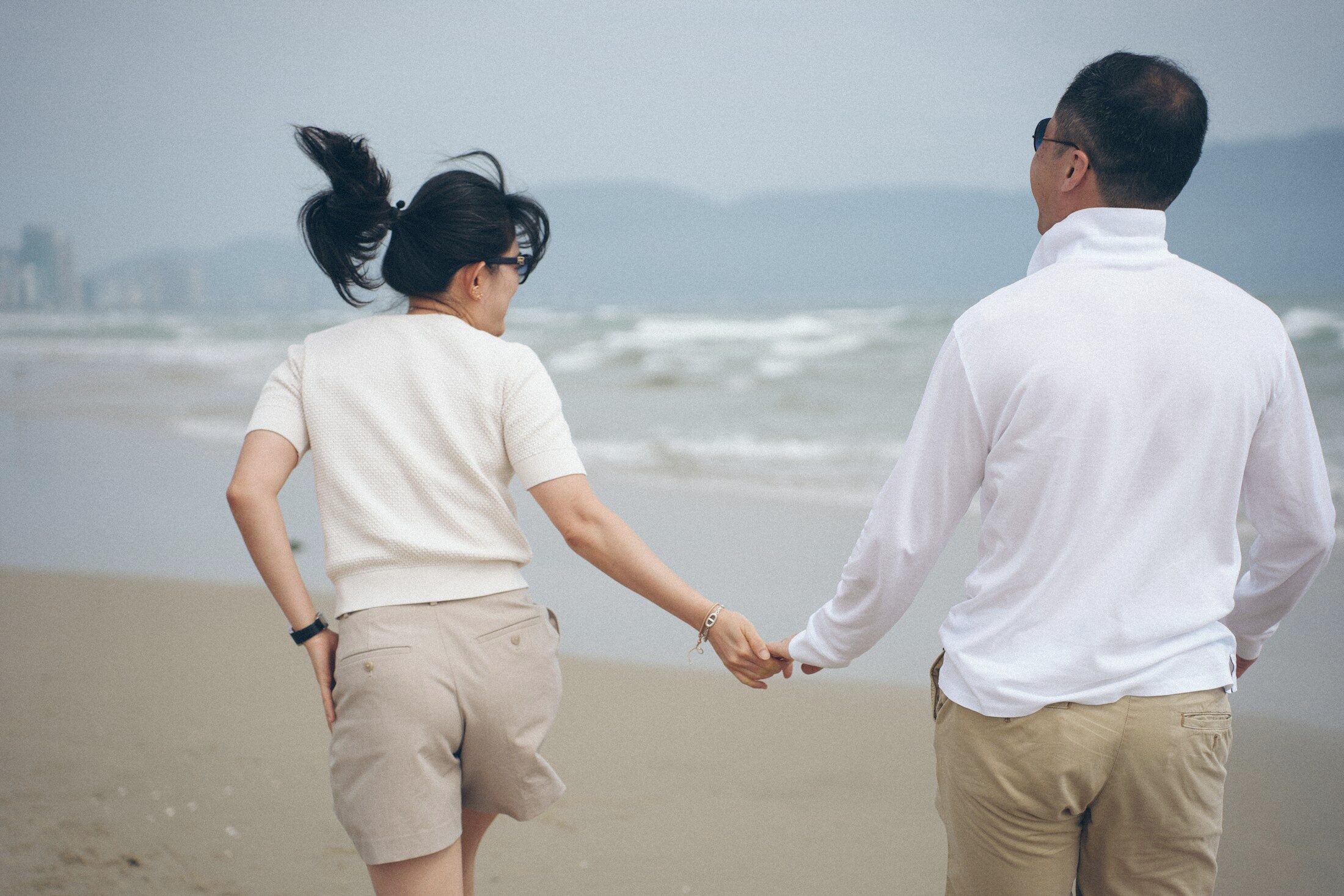 Two people walking hand in hand along a beach. Illustrative stock photograph, not an Almajour member